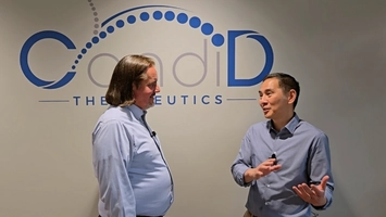 Two professionals in discussion before a Candid Therapeutics wall logo in a corporate office setting